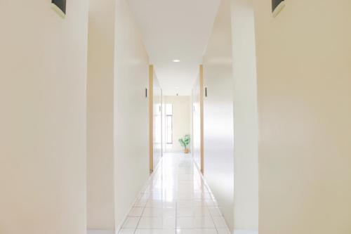a hallway with white walls and a white tile floor at LeGreen Suite Waihaong in Ambon