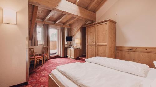 a bedroom with a bed and a desk and a window at Hotel Auhof Kappl in Kappl