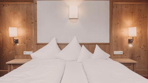 a large white bed with white pillows on it at Hotel Auhof Kappl in Kappl