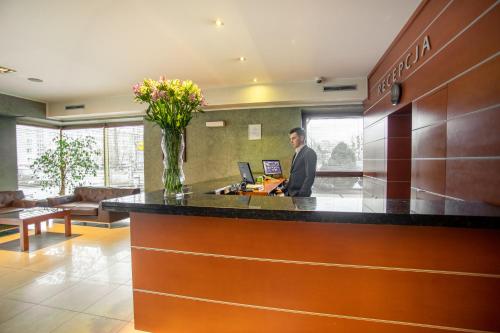 a man standing at a counter in a lobby at Business Hotel Vega Wrocław in Wrocław