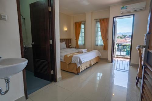 a bedroom with a bed and a sink and a bathroom at Dago's Hill Hotel in Bandung