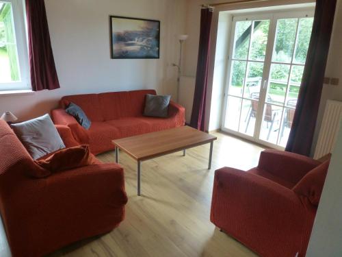 a living room with two red couches and a table at vila krkonoše in Cerny Dul