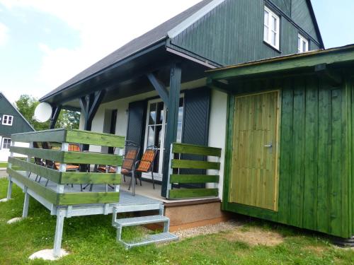 a green house with a wooden door and a bench at vila krkonoše in Cerny Dul