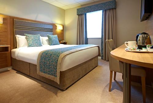a hotel room with a large bed and a table at The Briar Court Hotel in Huddersfield