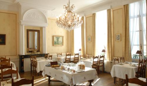una sala da pranzo con tavoli, sedie e lampadario a braccio di Hotel Patritius a Bruges