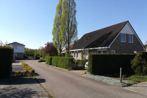 a house with a tree on the side of a road at Vakantiehuis Horsterwold in Zeewolde