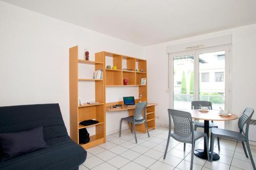 a living room with a couch and a table and a desk at Séjours & Affaires Annecy Le Pont Neuf in Annecy