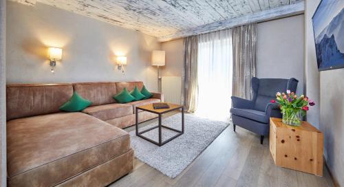 a living room with a brown couch and a blue chair at Landhotel zum Bad in Krün