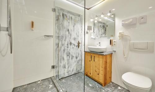 a bathroom with a shower and a toilet and a sink at Landhotel zum Bad in Krün