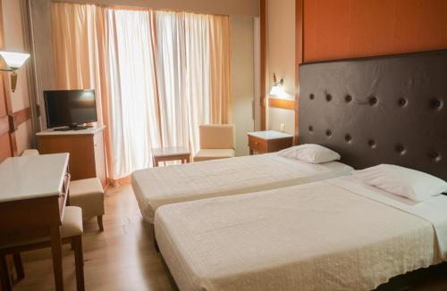 a hotel room with two beds and a television at Park Hotel in Volos