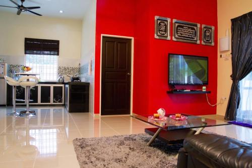a living room with a red wall at Homestay Hj Esmon Parit Raja UTHM in Batu Pahat