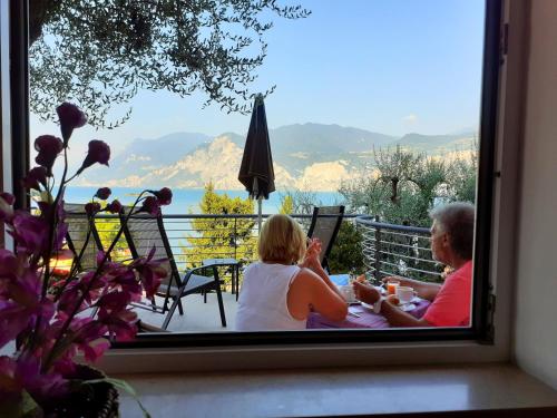 Un hombre y una mujer sentados en una mesa mirando por una ventana. en Hotel Antonella, en Malcesine
