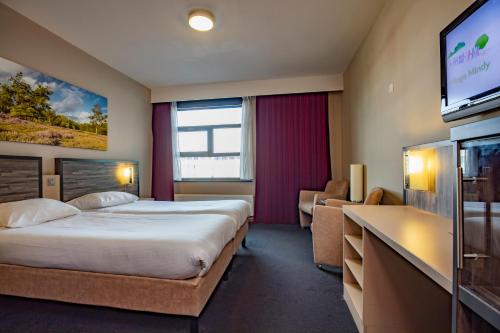 a hotel room with a bed and a flat screen tv at Fletcher Wellness-Hotel Trivium in Etten-Leur