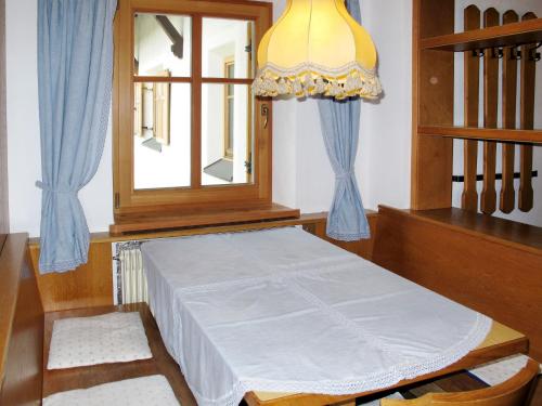 Ce lit se trouve dans un dortoir doté d'une fenêtre et d'un lustre. dans l'établissement Apartment Zollerhof - OLA192 by Interhome, à Niederolang