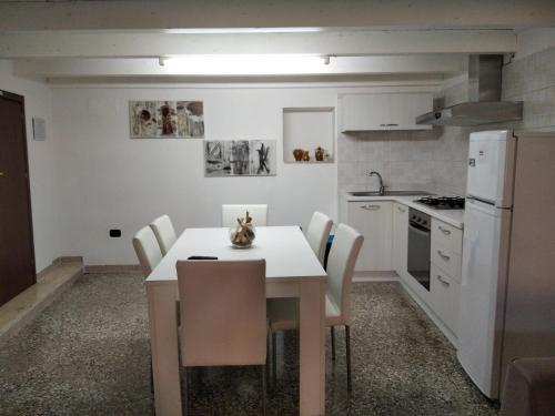 カロヴィーニョにあるb&b La Lucertola casa vacanzeのキッチン(白いテーブル、椅子付)