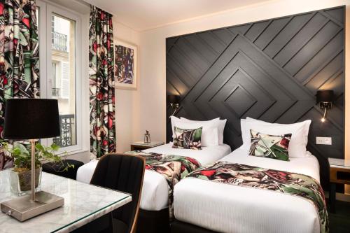 a hotel room with two beds and a table at H&ocirc;tel des Arts Montmartre in Paris