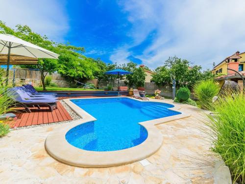 a swimming pool in a yard with chairs and an umbrella at Holiday Home Loreta by Interhome in Čabrunići