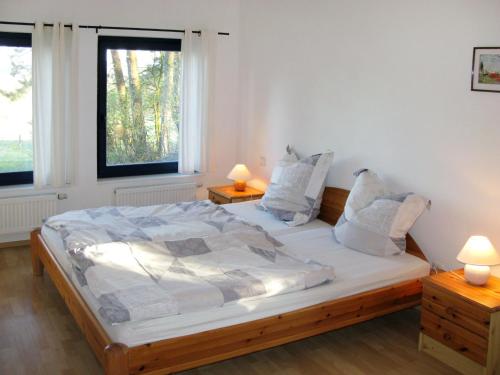 a bedroom with a large bed with two windows at Holiday Home Silz am Fleesensee-3 by Interhome in Silz
