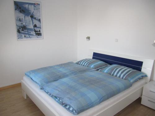 un letto con una coperta blu a quadri e due cuscini di Ferienwohnung Salzmann a Innsbruck