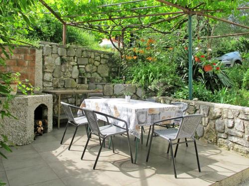 a table and chairs in a garden with a stone wall at Apartment Branka - MOD206 by Interhome in Mošćenice