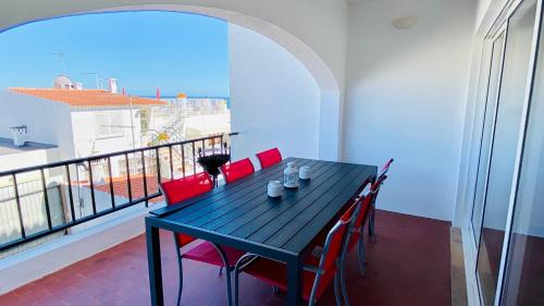 einen schwarzen Tisch mit roten Stühlen auf dem Balkon in der Unterkunft Cerro by Check-in Portugal in Albufeira