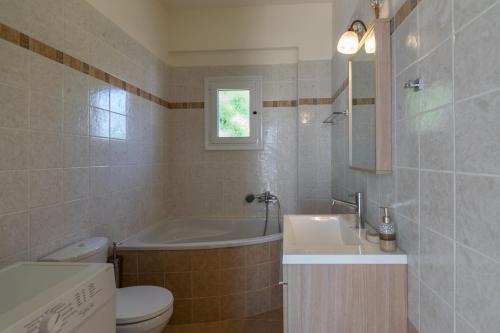ein Badezimmer mit einer Badewanne, einem WC und einem Waschbecken in der Unterkunft Haravgi 3 Bedrooms Villa in Agia Triada