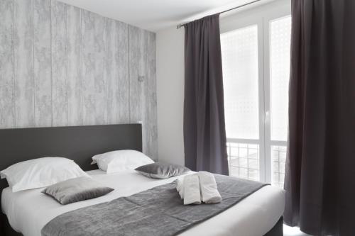 um quarto com uma cama com almofadas e uma janela em Lille City Hotel em Lille
