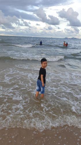 a young boy standing in the water at the beach at Quốc Ân Motel in Long Hai