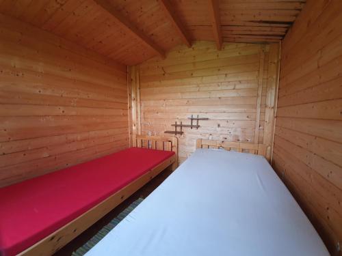 Cabaña de madera pequeña con cama roja en Lõunamatkad, en Kiidjärve