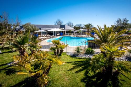 uma imagem de uma piscina com palmeiras em M&V Resort Camping em Langrune-sur-Mer