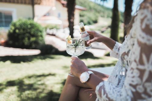 una mujer sosteniendo una copa de vino con una botella en Hotel Am Sonneck, en Lagundo