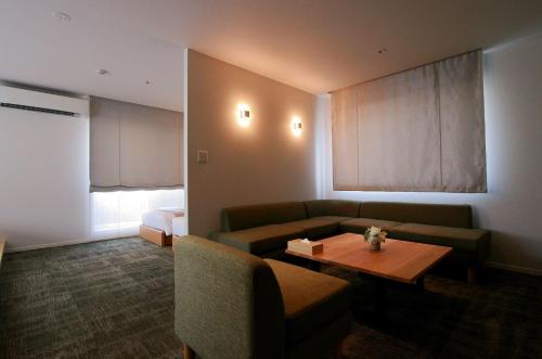 a living room with a couch and a table at GRAND BASE Okayama Ekimae in Okayama