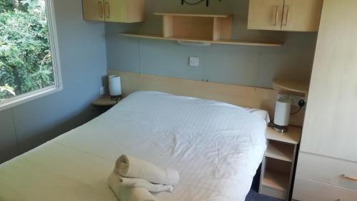 Un pequeño dormitorio con una cama blanca y una ventana en Static Caravan for hire, budget friendly, en Edimburgo