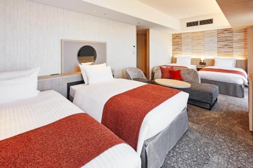 a hotel room with three beds and a couch at Hotel Emion Kyoto in Kyoto