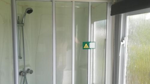 una puerta de ducha de cristal con una señal de advertencia en Static Caravan for hire, budget friendly, en Edimburgo