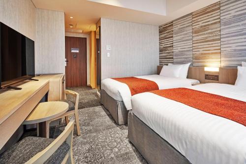 a hotel room with two beds and a television at Hotel Emion Kyoto in Kyoto
