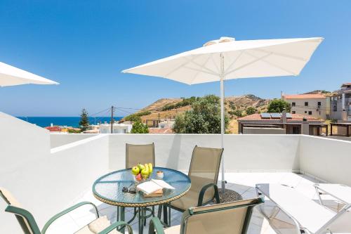 a patio with a table and chairs and an umbrella at Philoxenia Apartments in Panormos Rethymno