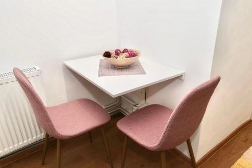 a table with two chairs and a bowl of fruit on it at Garsoniera in Cluj-Napoca