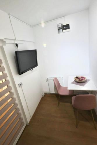 a room with a table and a tv on a wall at Garsoniera in Cluj-Napoca