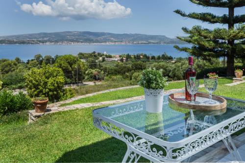 a glass table with a bottle of wine and wine glasses at Panorama Fanari studios and apartments in Argostoli