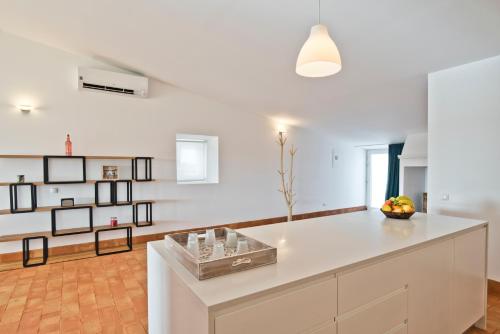 a white kitchen with a large white island in a room at Herdade do Barrocal de Baixo in Montemor-o-Novo