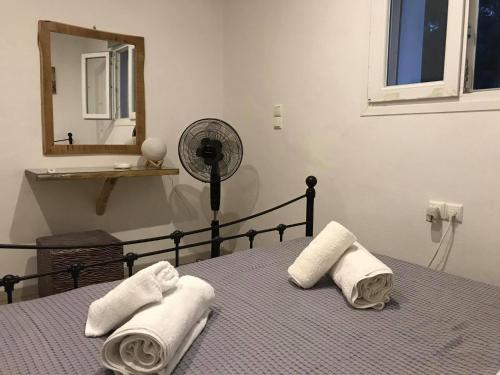 a bedroom with a bed with towels and a fan at Sarris Ligaridia Apartments in Naxos Chora