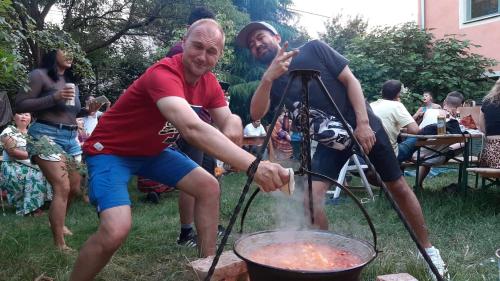 two men cooking food in a grill in a yard at Budapest Garden Hostel in Budapest