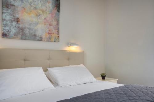 a bedroom with a white bed with a painting on the wall at Panorama Fanari studios and apartments in Argostoli