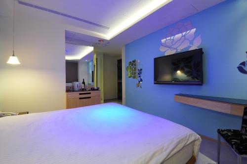 ein Schlafzimmer mit einem weißen Bett und einem TV an einer blauen Wand in der Unterkunft Hotel 20 Alley in Xindian