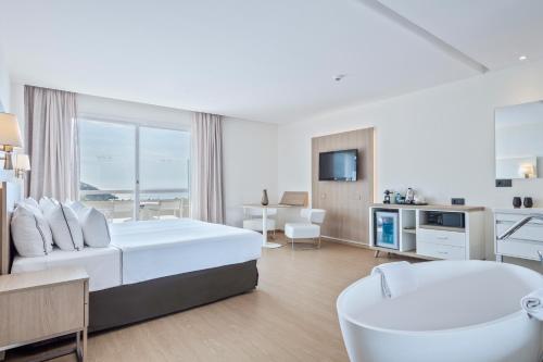 Cette chambre blanche comprend un lit et une chaise. dans l'établissement Melia Sitges, à Sitges