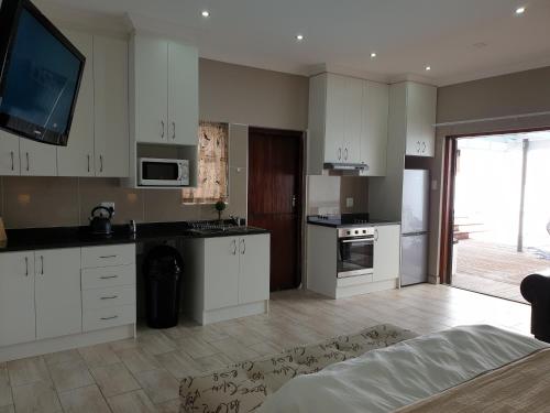 a kitchen with white cabinets and a tv on the wall at Pongola Road Self Catering Accommodation in Uitenhage