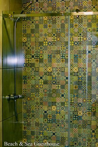 a bathroom with a shower with a mosaic wall at Beach & Sea Guesthouse in Espinho