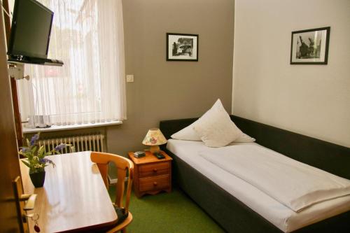 ein kleines Zimmer mit einem Bett und einem Tisch mit einer Lampe in der Unterkunft Hotel Meiendorfer Park in Hamburg