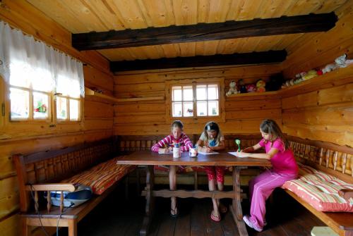 two girls sitting at a table in a log cabin at Apartmánový dom Slniečko in Liptovský Ján